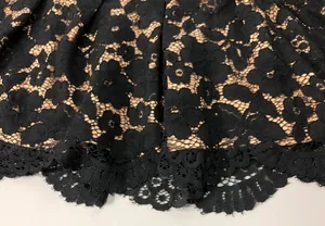 Close-up detail of delicate floral lace fabric and eyelash hem of a black skirt