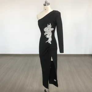 Detail of black one-shoulder dress with rhinestone floral appliqué and high slit.