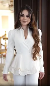 Vue détaillée du haut à basque blanc élégant avec broderie de perles complexe sur l'ourlet.