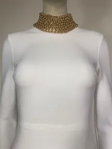 Close-up detail of a white bandage dress featuring a luxurious gold beaded stand collar