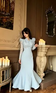 Elegant light blue lace long sleeve mermaid evening gown shown in a luxurious setting.
