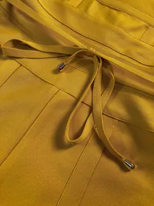 Macro detail of mustard yellow bandage jumpsuit with drawstring waist and metal tips