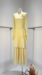 Elegant yellow long-sleeved tiered dress featuring a floral brooch and pleated details