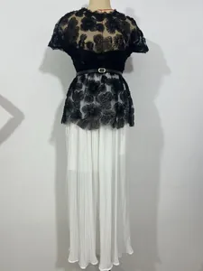 Close-up detail of an elegant black floral lace top paired with a white pleated skirt