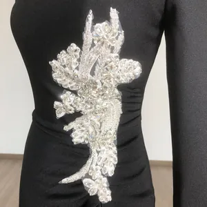 Detailed view of silver floral rhinestone applique on black long-sleeved bandage dress.