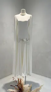 Gedetailleerd overzicht van een elegante witte avondjurk met cape-mouwen en borduursels