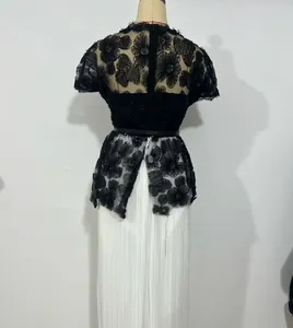Detailed back view of a stylish black floral lace overlay paired with white pleated skirt