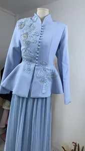 Detail view of light blue embroidered jacket with floral beadwork and pleated skirt