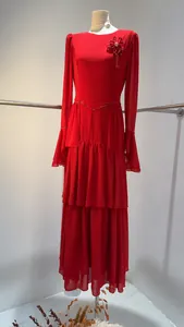 Elegant red tiered long-sleeved dress with floral brooch on mannequin