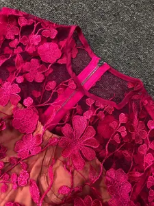 Close-up of magenta floral lace embroidery and back zipper on elegant dress detail.