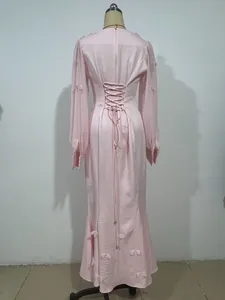 Dettaglio del retro di abito rosa a maniche lunghe con fiori 3D e lacci a corsetto