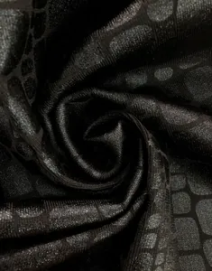 Macro view of premium black bandage dress fabric with a shiny foil geometric pattern.