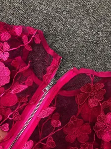 Detailed view of magenta lace dress with 3D floral embroidery and sturdy metal zipper.