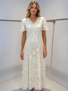 Full view of elegant white lace dress with fringe details on mannequin.