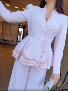 Ensemble élégant rose clair avec blazer à basque perlé et pantalon large assorti.