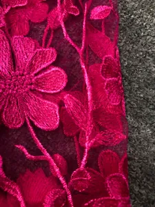 Detailed macro shot of fuchsia floral embroidery on premium elegant lace fabric detail