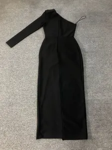 Detailed flat lay view of a black one-shoulder long-sleeve evening gown on gray carpet