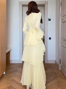 Elegant pale yellow long-sleeve tiered dress for women with ruffled layers and back bow detail.