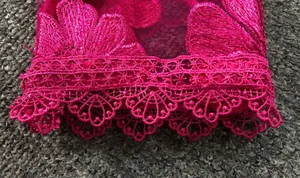 Macro view of elegant magenta 3D floral embroidery and lace trim on mesh fabric