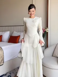 Elegant white long-sleeved maxi dress featuring a floral applique and tiered skirt design