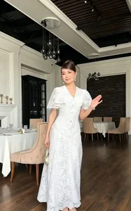Elegant white lace dress with fringe sleeves shown in a luxury dining setting.