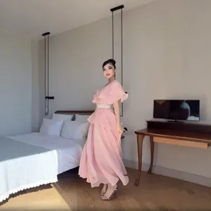 Elegantes rosa gestuftes Maxikleid mit Rüschen und Gürtel in modernem Schlafzimmer