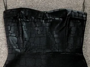 Macro detail shot of black bodycon tube dress featuring a metallic crocodile scale texture