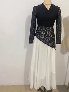 Detailed view of an asymmetrical black lace bodice and long sleeves on a white dress