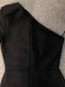 Macro view of the neckline and zipper on a black one-shoulder bandage evening dress