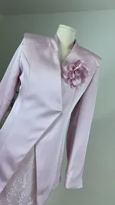 Detailed view of light pink satin blazer featuring a decorative 3D floral brooch