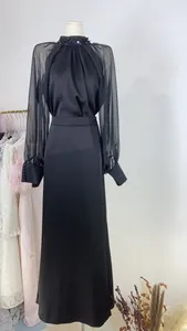 Detailed view of elegant French black evening gown featuring sheer sleeves and beaded collar
