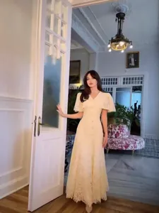 Elegant cream lace long dress with short sleeves and fringe details in vintage interior
