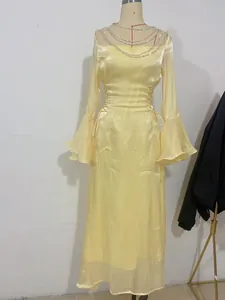 Vista dettagliata del vestito giallo a maniche lunghe con scollatura decorata con catene