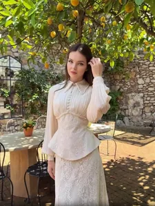 Close-up detail of elegant cream chiffon pleated blouse and matching lace peplum skirt set