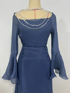 Dettaglio di abito blu navy a maniche lunghe con scollo a catena di paillettes e maniche a campana