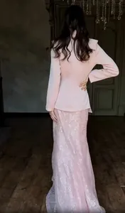 Back view of pink textured blazer and lace maxi skirt set in elegant indoor setting