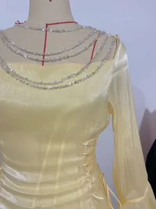 Dettaglio di un abito giallo scintillante con elegante catena di paillettes sullo scollo