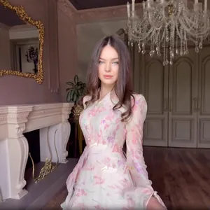 Detail shot of an elegant long-sleeved floral print dress worn in a luxury room setting.
