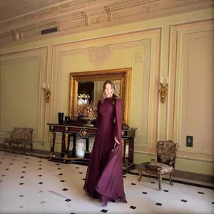 Elegantes, tiefburgunderrotes, langärmeliges Abendkleid in einem luxuriösen Schlosssaal