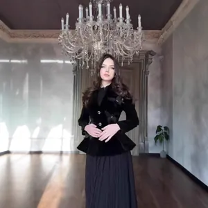 Elegant model wearing a vintage black velvet jacket with butterfly accents and a pleated skirt