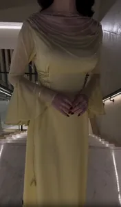 Dettaglio di un abito giallo sfiancato con un elegante colletto a catena di perle.