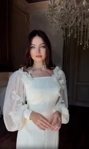 Elegante abito bianco da sera con maniche a sbuffo trasparenti e applicazioni floreali.