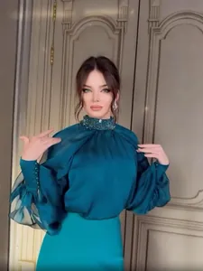 Elegant teal silk evening gown detail featuring beaded high neck and pleated sleeves