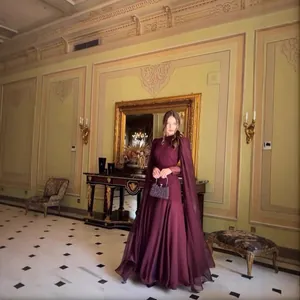 Elegantes burgunderfarbenes Abendkleid mit Cape-Ärmeln in einer prunkvollen Schlosshalle stehend