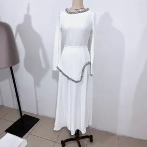 Detailansicht eines weißen Langarmkleides mit elegantem Strassbesatz am Kragen