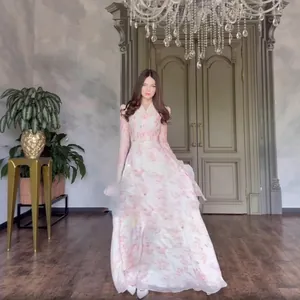 Elegant long-sleeved floral maxi dress with ruffle detailing in a grand interior setting