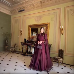 Elegantes pflaumenfarbenes Abendkleid mit Kap-Ärmeln in einem luxuriösen Festsaal