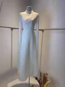 Gros plan d'une élégante robe longue blanche à col haut avec des manches longues fluides