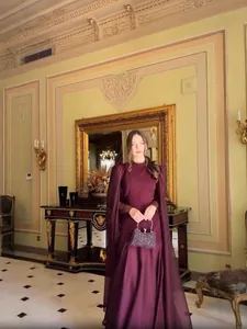Elegantes burgunderrotes langes Kleid mit Cape-Ärmeln und hohem Ausschnitt im Luxus-Ambiente