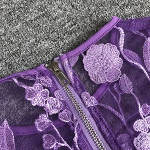 Close-up detail of purple floral embroidery and lace on a dress with metal zipper